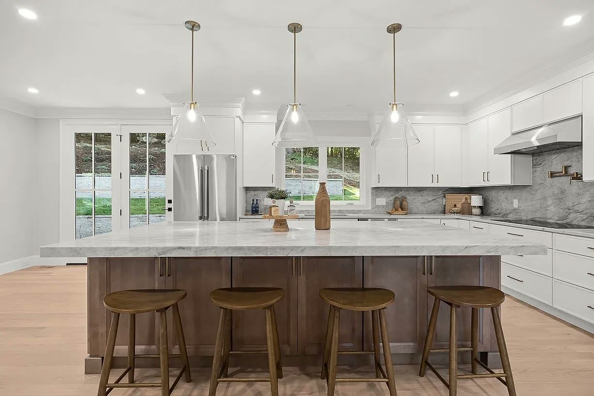 White perimeter cabinetry with a wood island and white veined stone worktops
