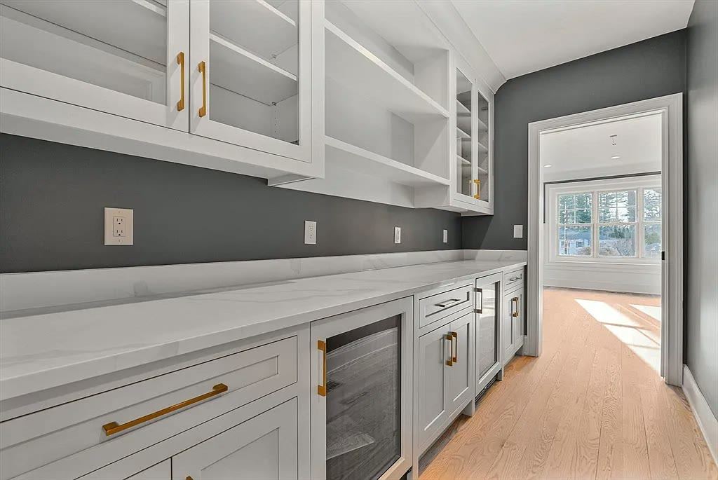 White cabinetry with brass hardware and white veined stone against a dark wall